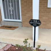 A no soliciting sign with a welcome mat in the background