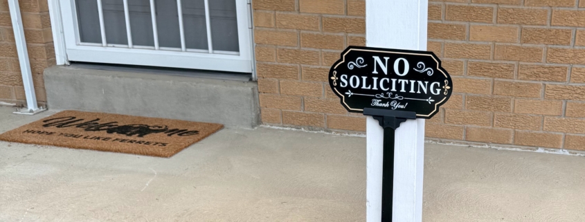 A no soliciting sign with a welcome mat in the background